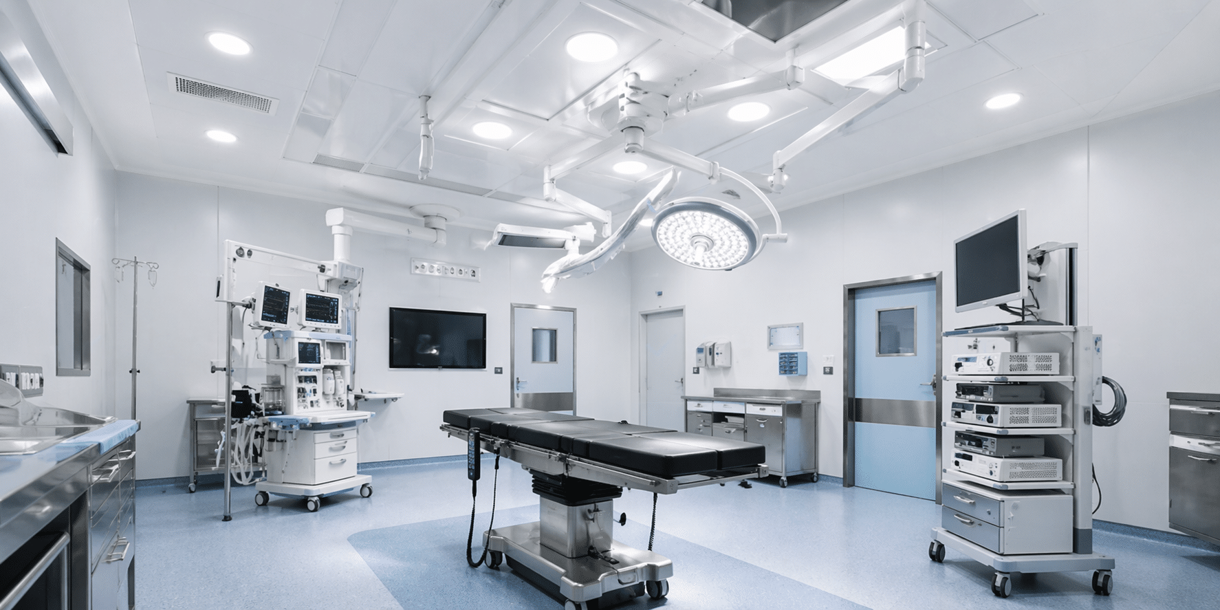 Bright operating room with a central black surgical table, ceiling lights, and medical equipment carts on wheels.